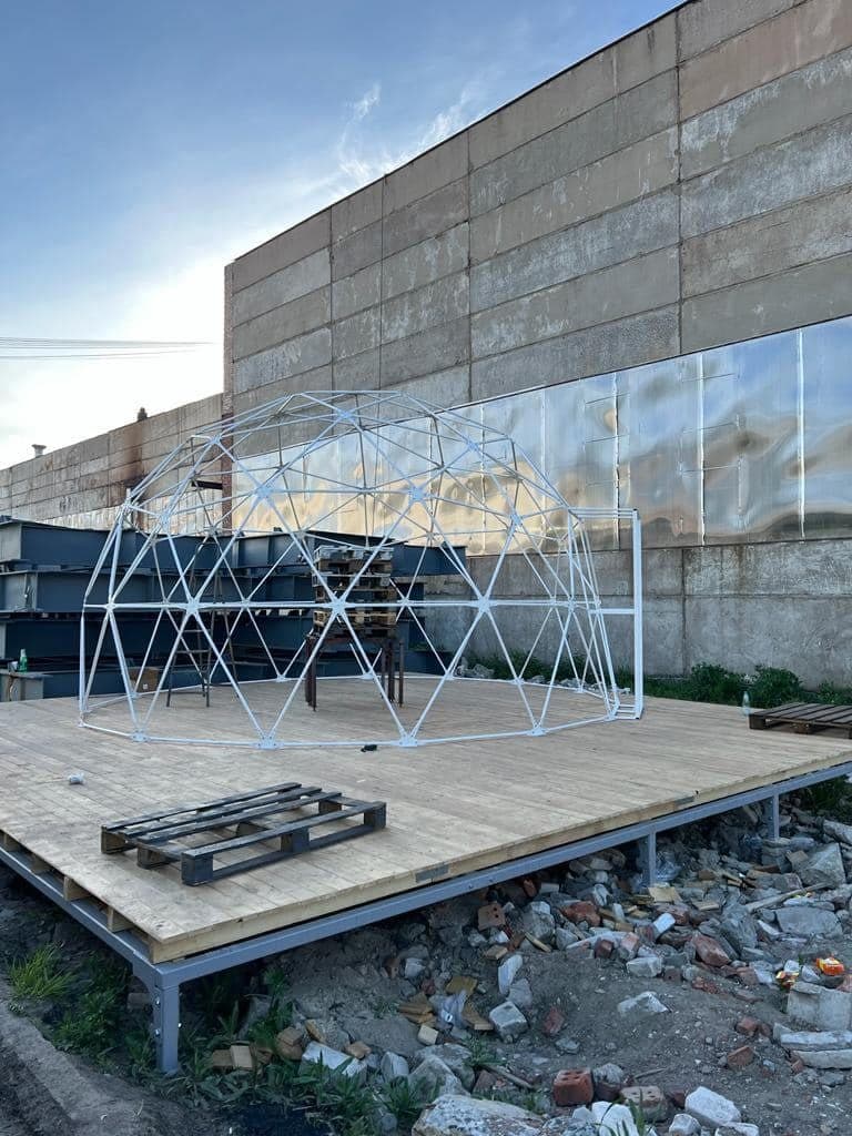 White steel geodesic dome frame on a timber platform