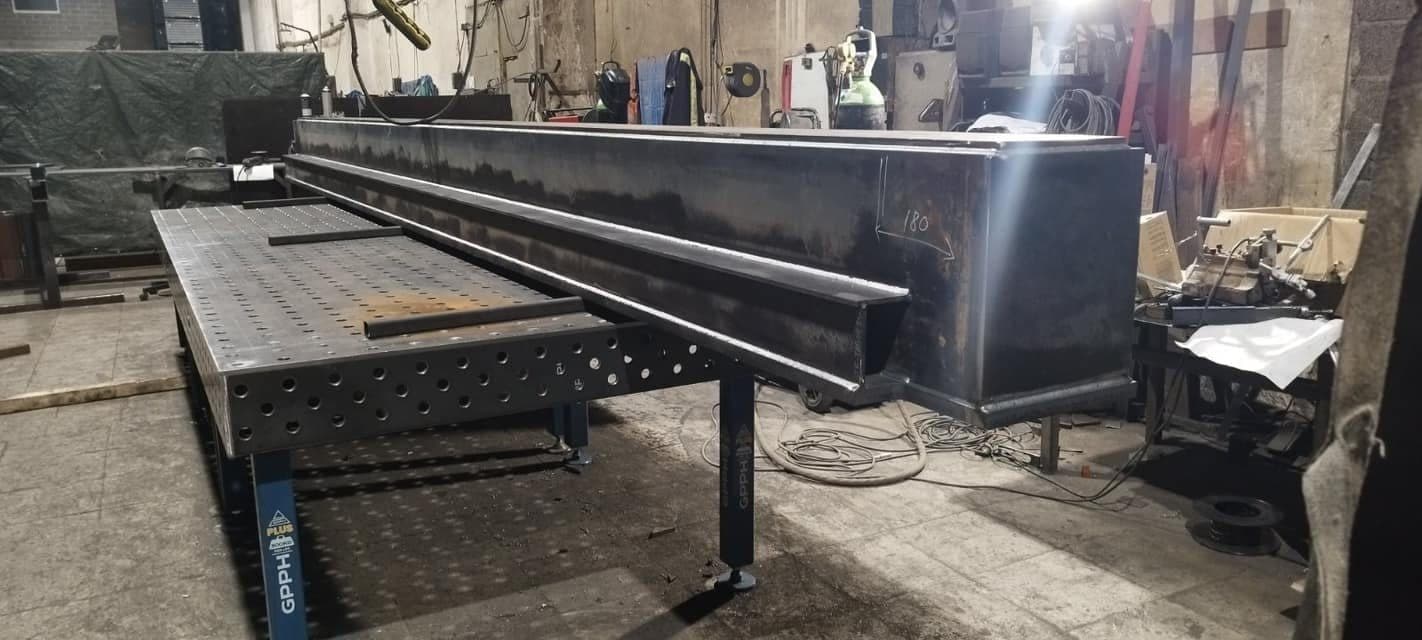 Long black steel beam on a welding table in the workshop