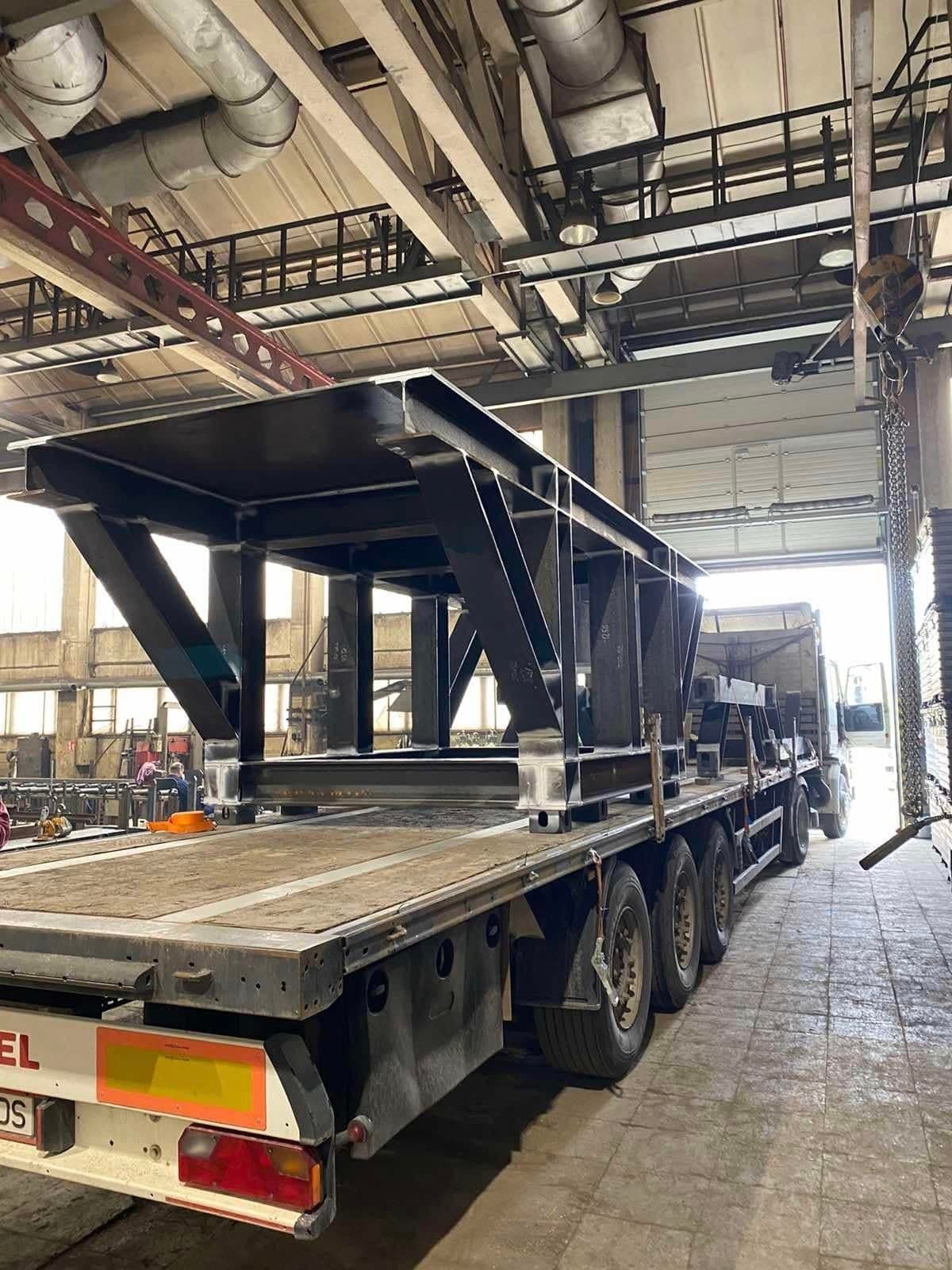 Steel frame structure on a flatbed trailer at the workshop door