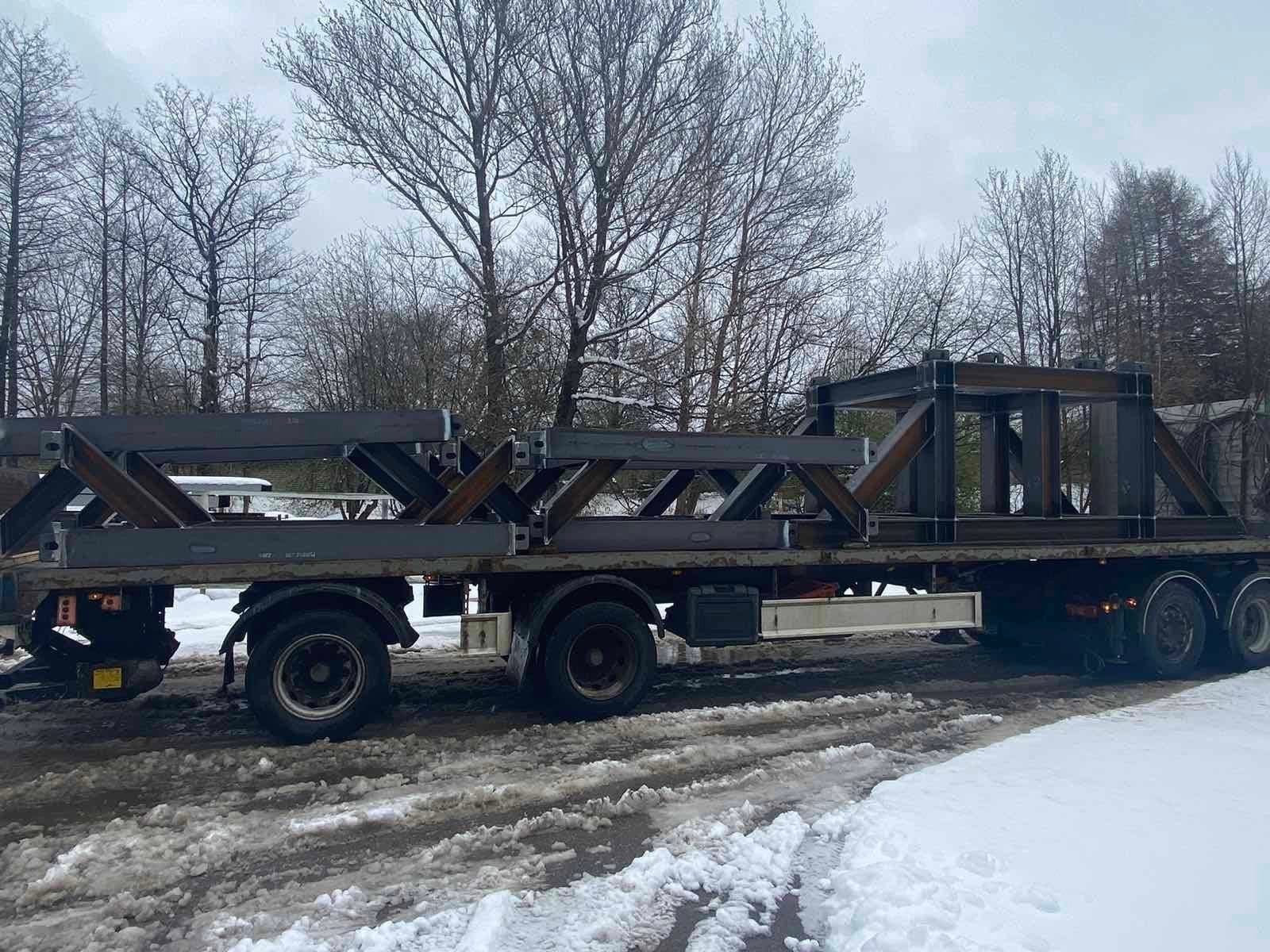 Dark steel trusses on a flatbed trailer in the snow