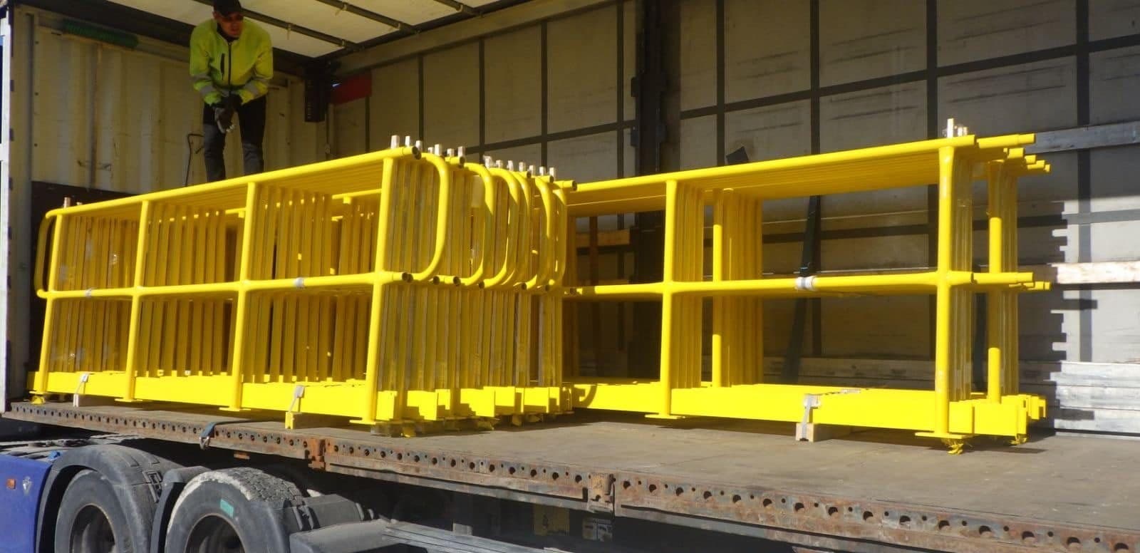 Yellow-painted steel railing frames loaded on a truck