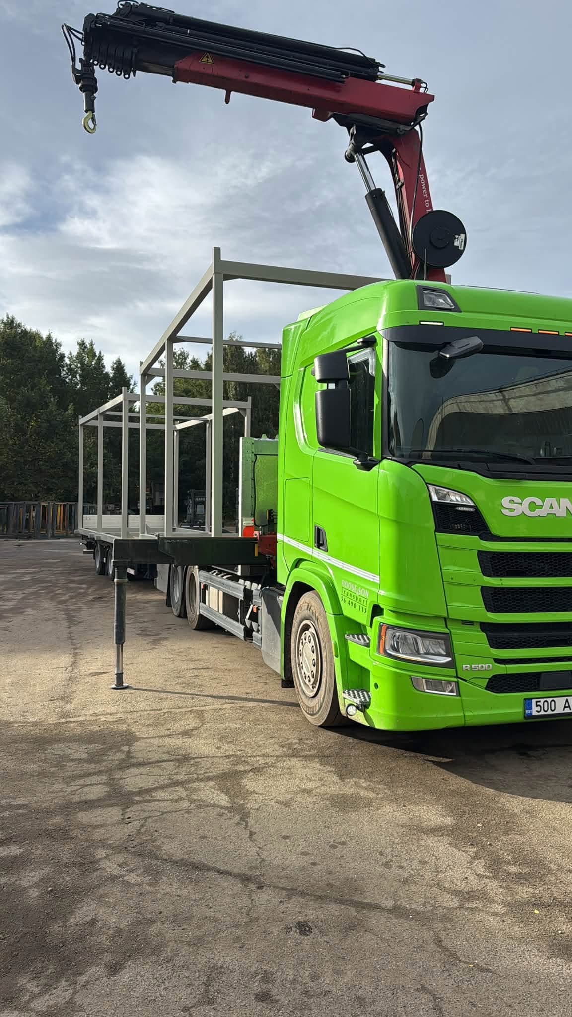 Truck-mounted crane next to a steel frame structure on a green Scania at the Novatex yard in Tallinn