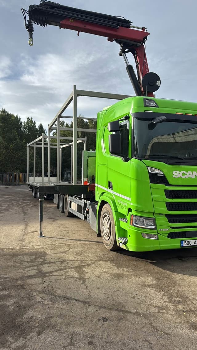 Truck-mounted crane next to a steel frame structure on a green Scania at the Novatex yard in Tallinn
