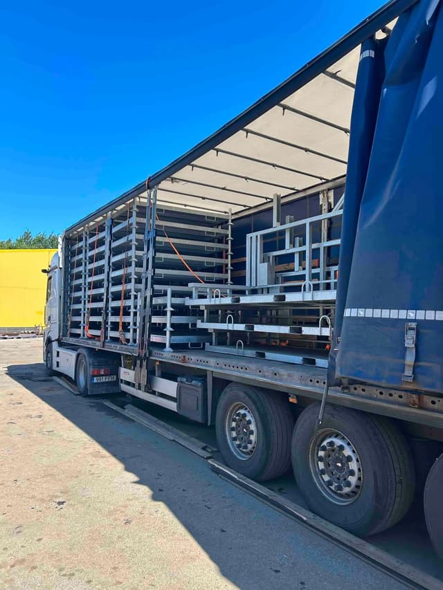 Side view of a curtainsider trailer loaded with steel frames at the Novatex yard in Tallinn