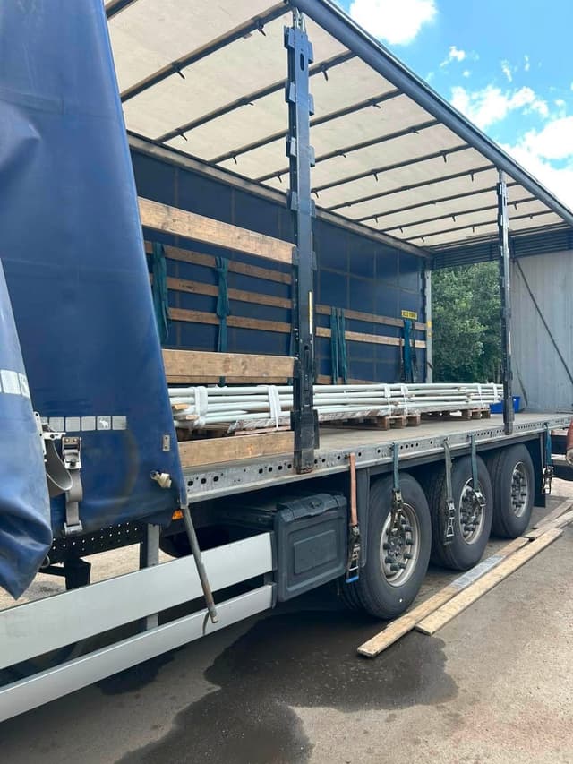 Steel parts on timber bearers in an open curtainsider trailer at the Novatex yard in Tallinn