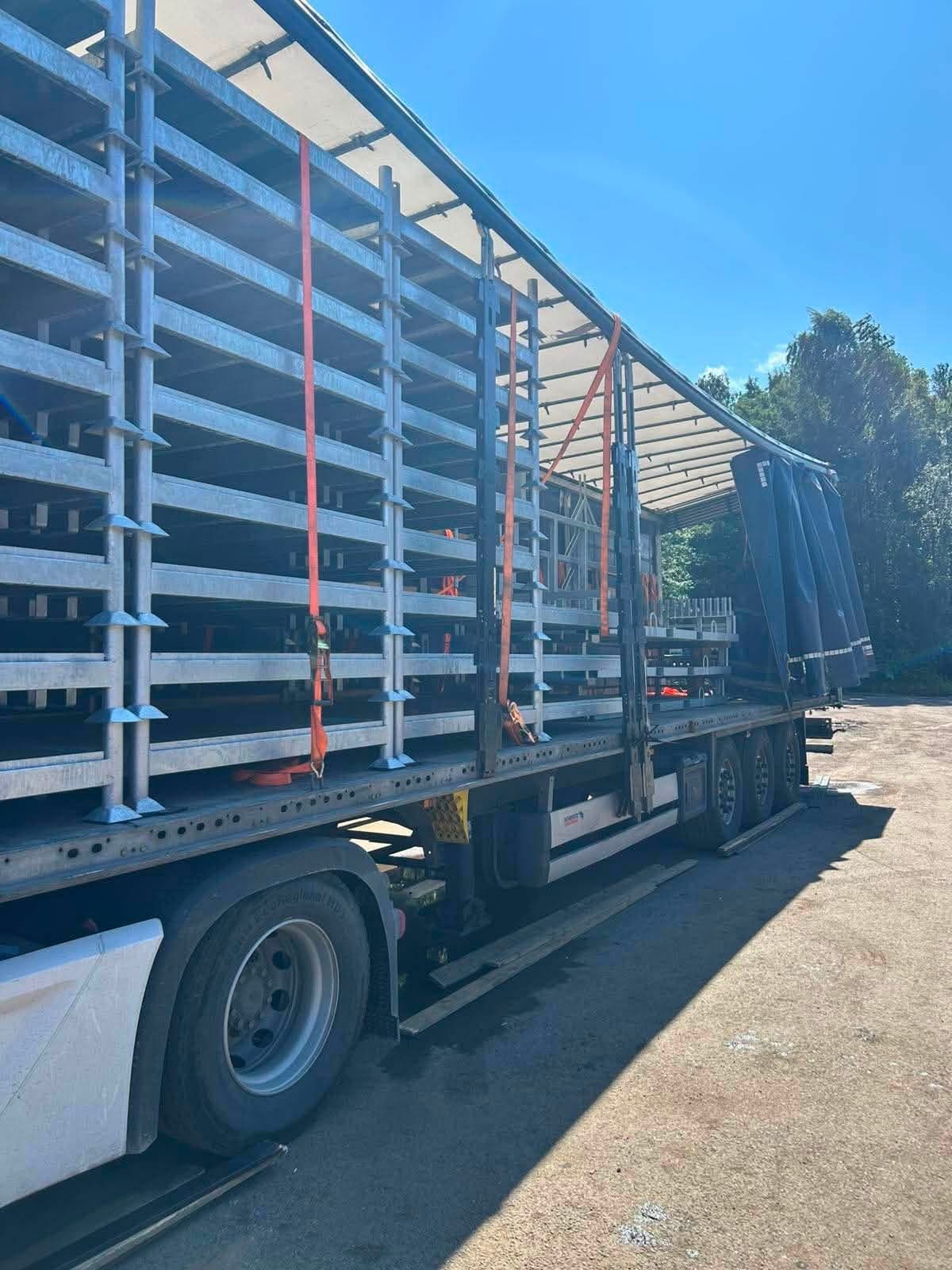 Rows of galvanized steel frames strapped inside an open curtainsider trailer at the Novatex yard in Tallinn