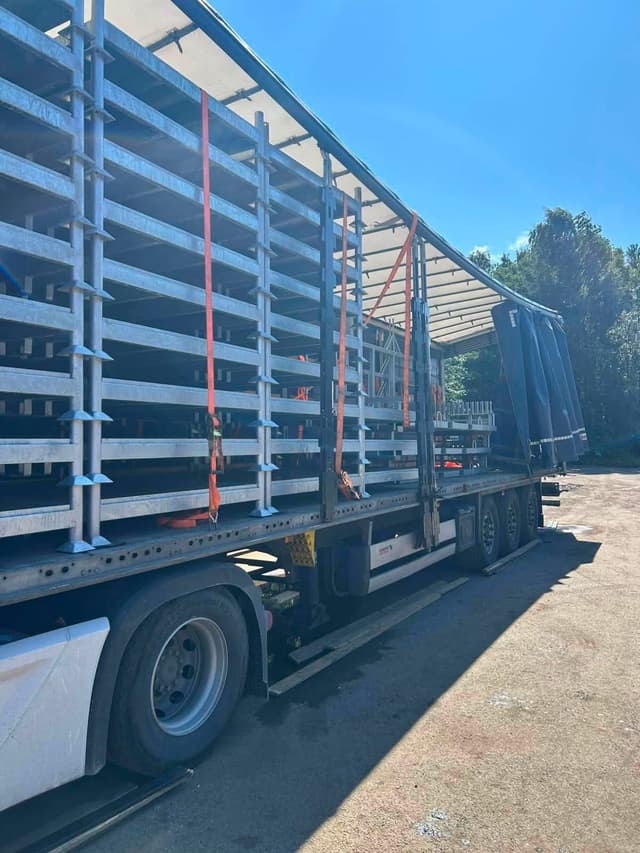 Rows of galvanized steel frames strapped inside an open curtainsider trailer at the Novatex yard in Tallinn