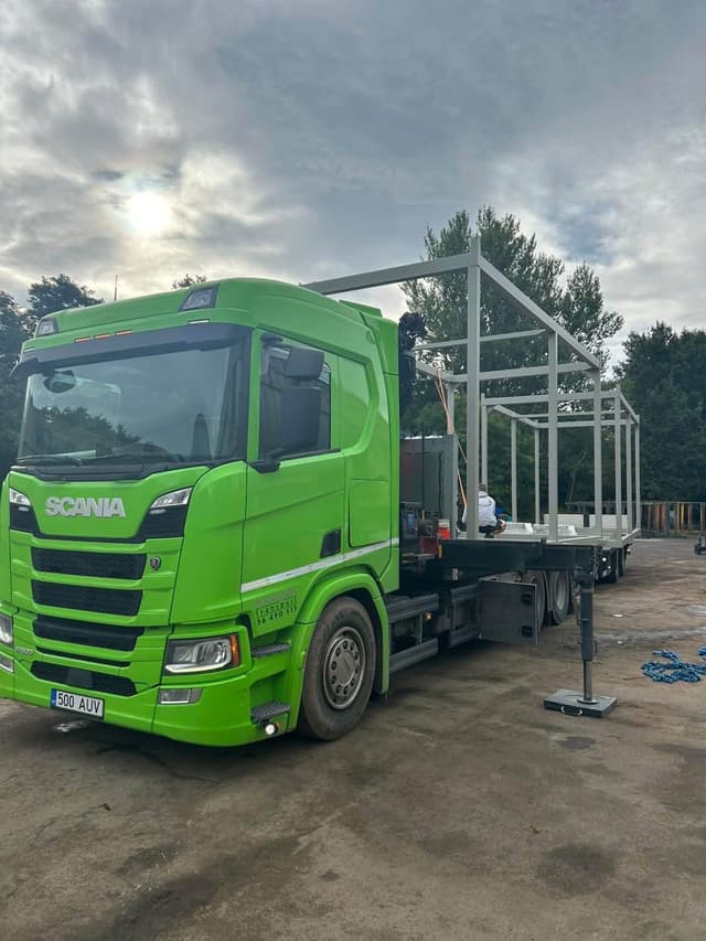 Green Scania crane truck carrying a welded steel frame structure at the Novatex yard in Tallinn