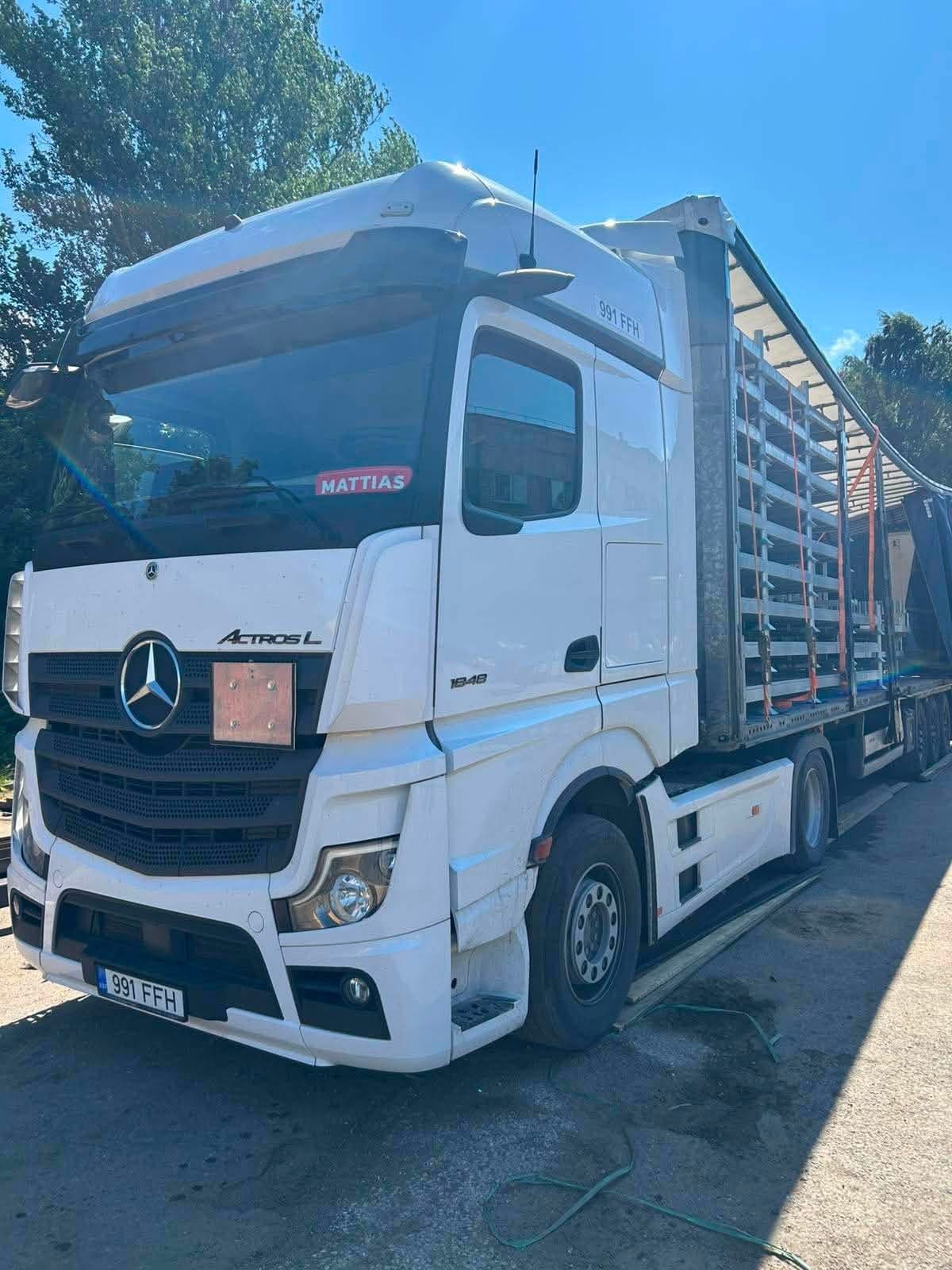 White Mercedes-Benz Actros with its curtainsider loaded with steel frames at the Novatex yard in Tallinn